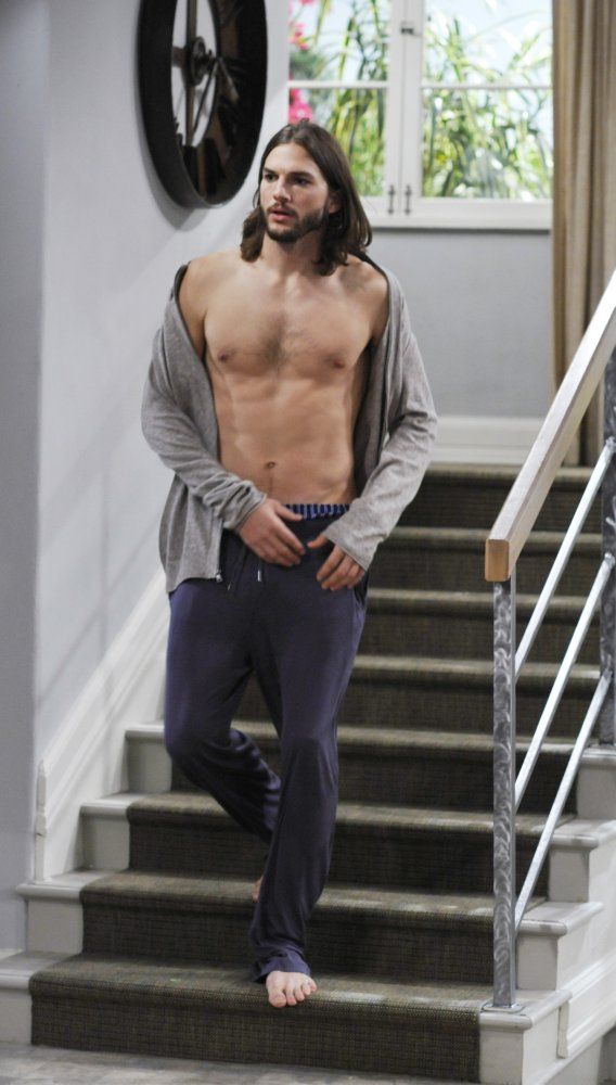 a shirtless man standing on the stairs with his hands in his pockets