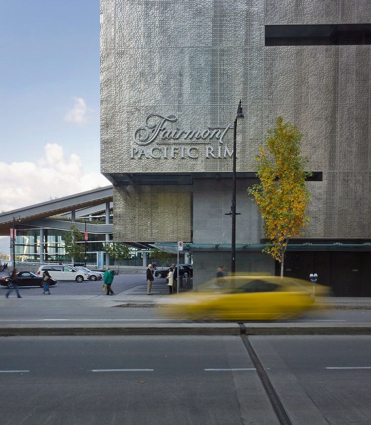 a yellow car driving past a tall building