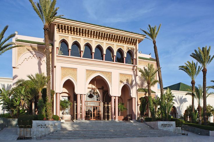 a large building with palm trees in front of it and stairs leading up to the entrance