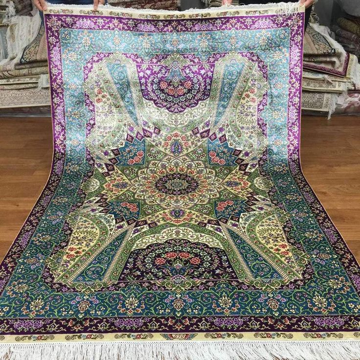 an intricately designed rug is displayed on the floor in front of a pile of pillows