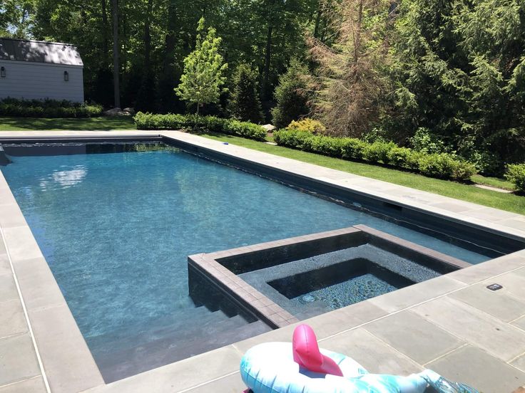 an inflatable toy floats near the edge of a swimming pool surrounded by greenery