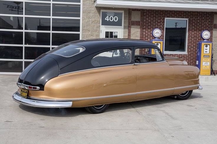 an antique car is parked in front of a gas station with no one around it