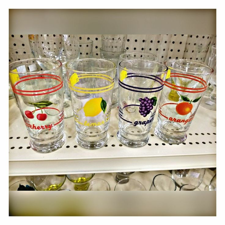 there are many glasses on the shelf in the store, each with an apple and grapes design