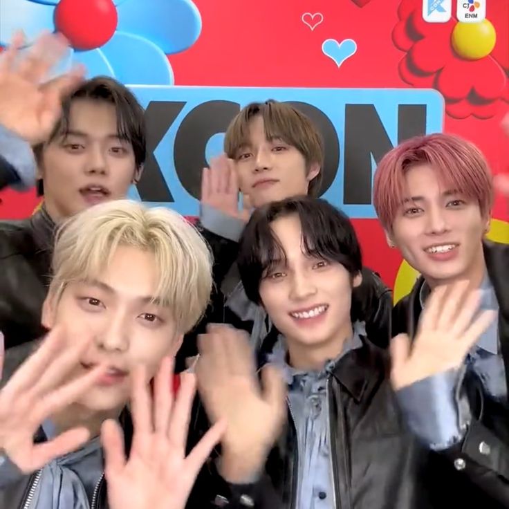 group of young men posing in front of a red and blue background with their hands up