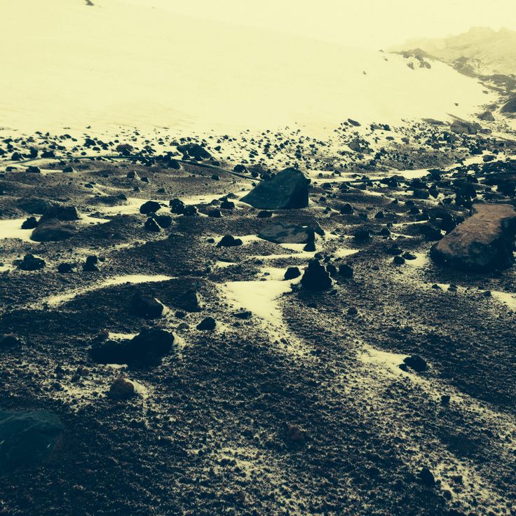 the ground is covered in mud and rocks with snow on top, as seen from above