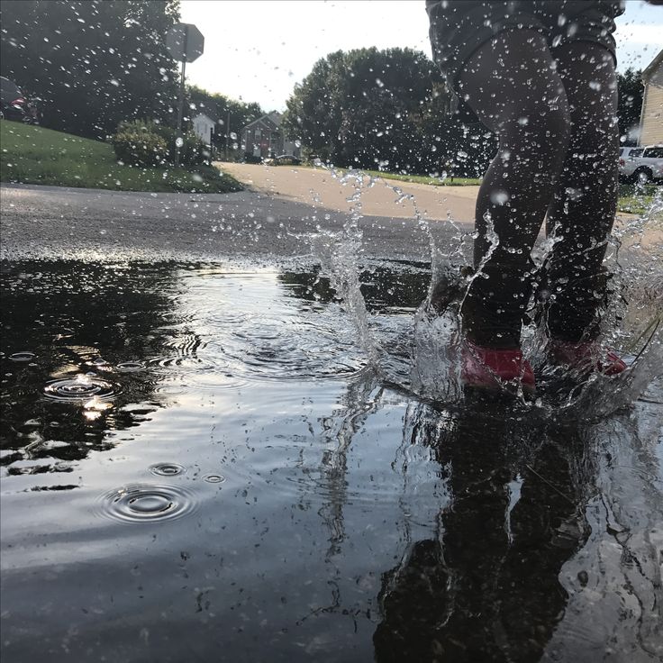 a person standing in the middle of a puddle with their feet up and water splashing on them