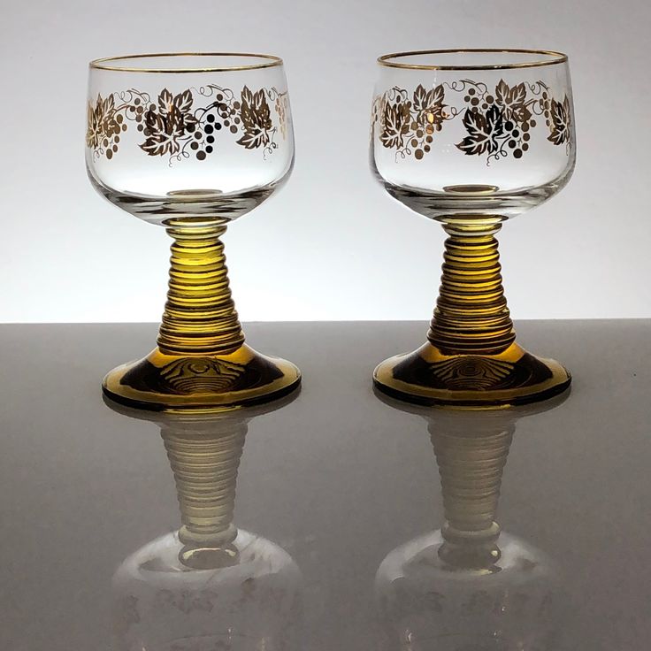 two glass goblets sitting on top of a table next to eachother