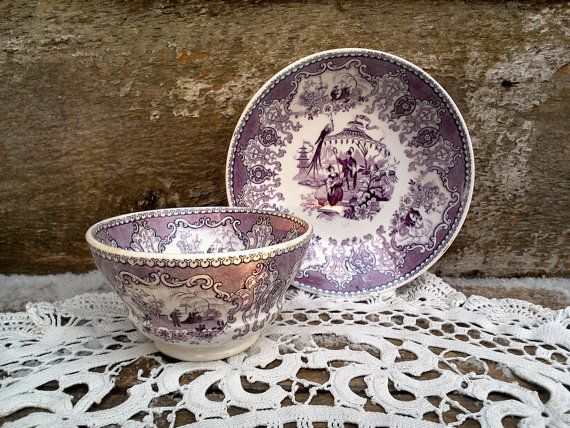 two purple and white dishes sitting on top of a doily