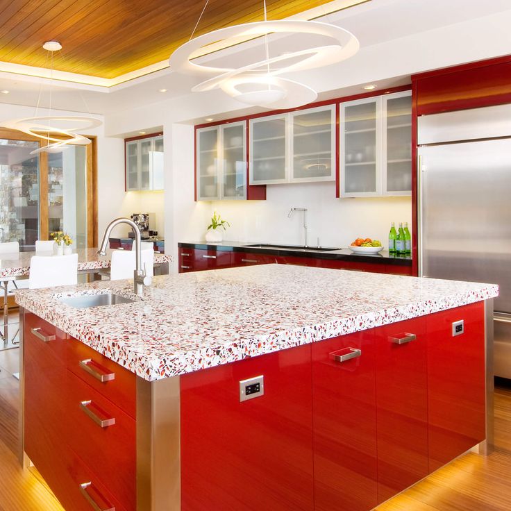 a kitchen with red cabinets and white counter tops, stainless steel refrigerator and dishwasher