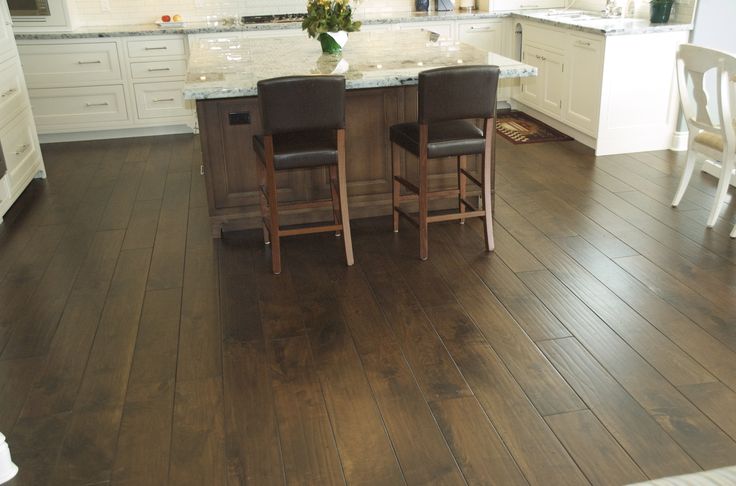 two chairs are sitting at the center of a kitchen island with marble counter tops and white cabinets