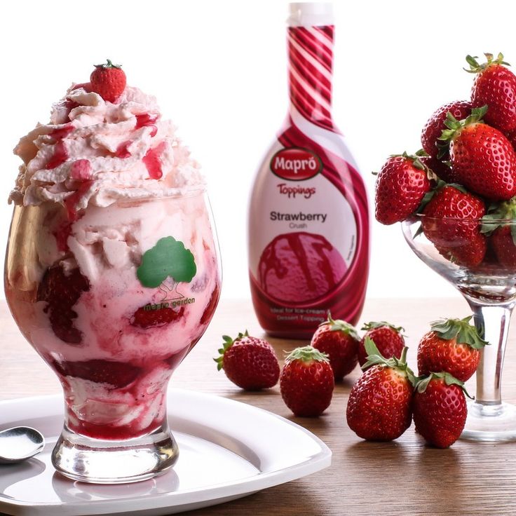 strawberry ice cream in a glass with strawberries next to it