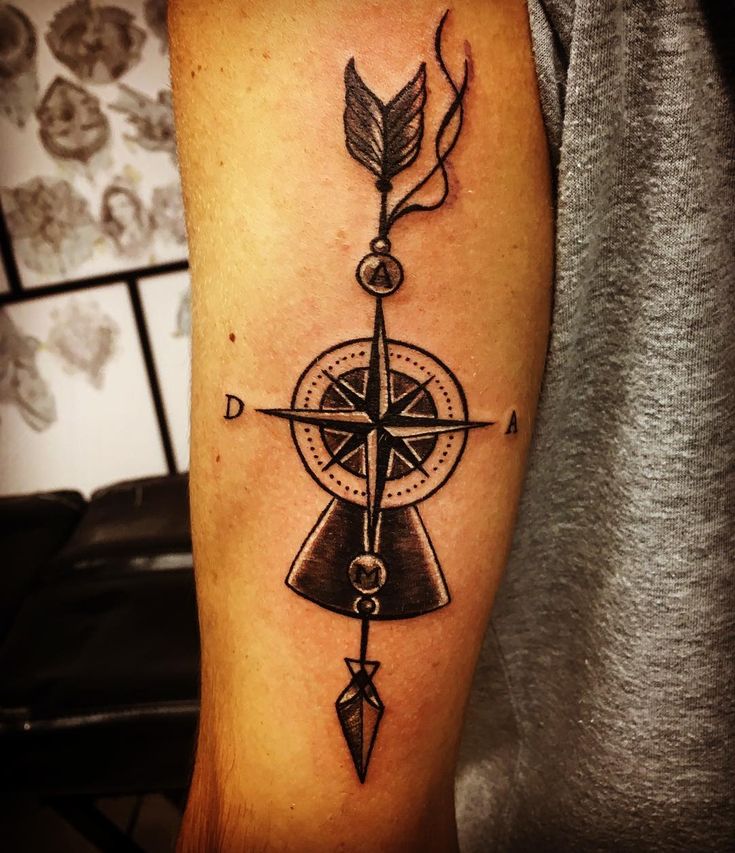 a man's arm with a compass and arrow tattoo on it