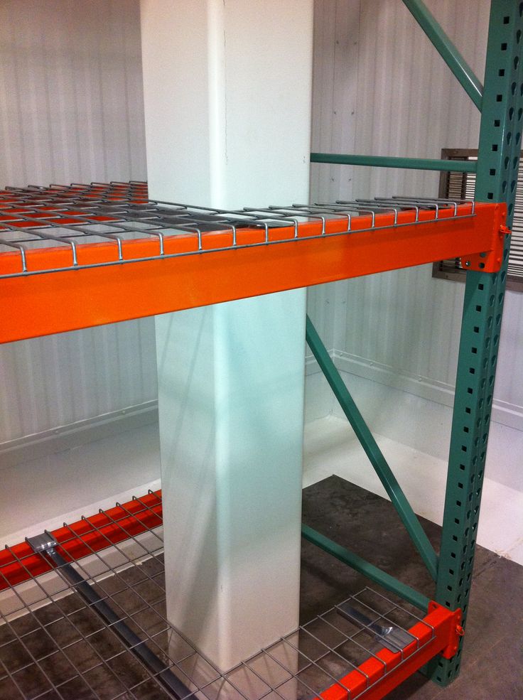 an orange and white shelf in a room with metal shelving on it's sides