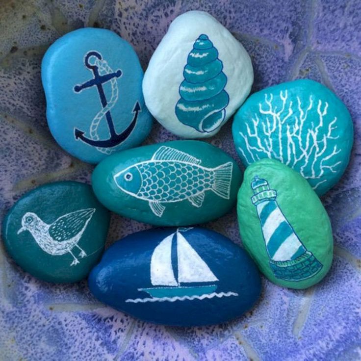 some rocks with different designs on them and one has an anchor, seagull, fish