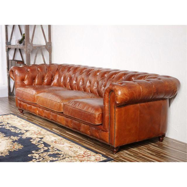 a brown leather couch sitting on top of a wooden floor next to a blue rug