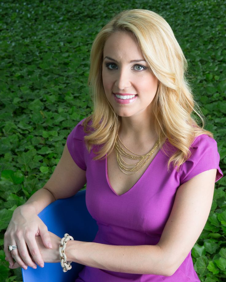 a woman in a purple dress is sitting on a blue chair and smiling at the camera