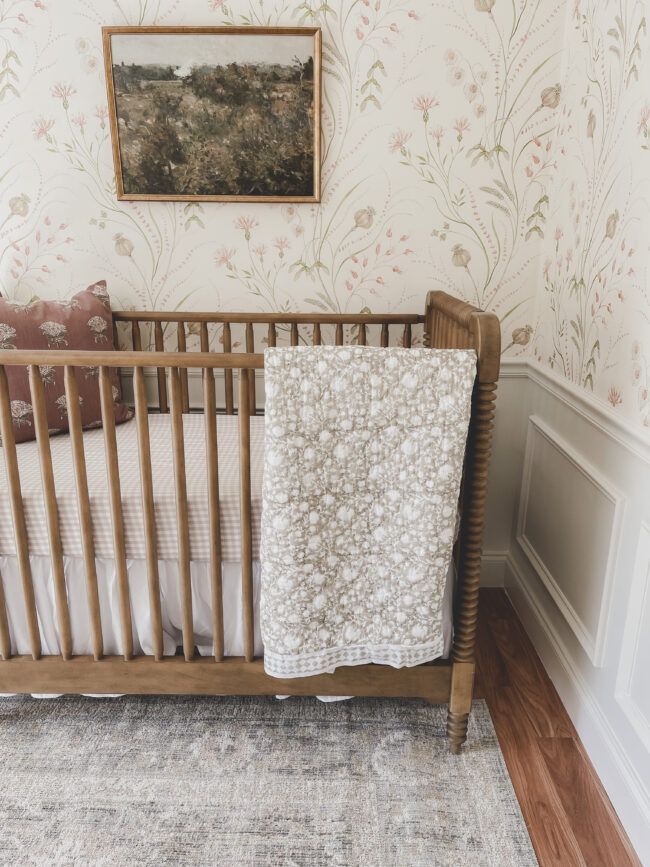 a baby's crib in the corner of a room with floral wallpaper