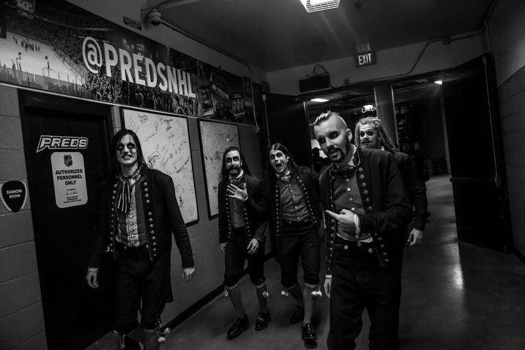 five men in black and white are walking down the hallway with their faces covered by fake teeth