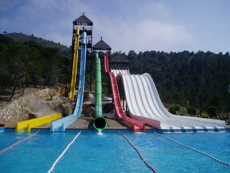 an inflatable water slide next to a swimming pool with blue water and hills behind it