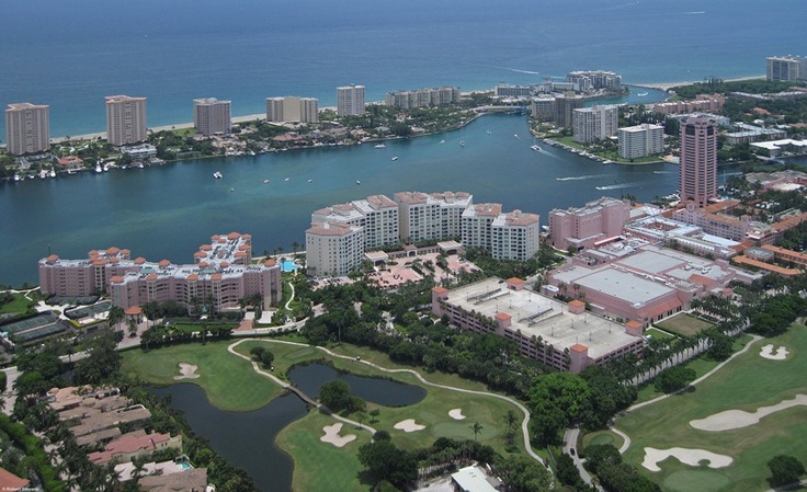 an aerial view of a golf course and the water in front of buildings with boats on it