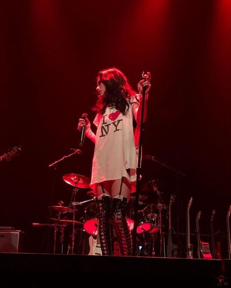 a woman standing on top of a stage holding a microphone in front of red lights