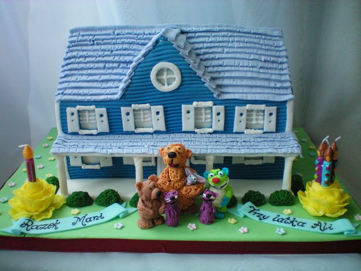 there is a cake made to look like a house with teddy bears on the lawn