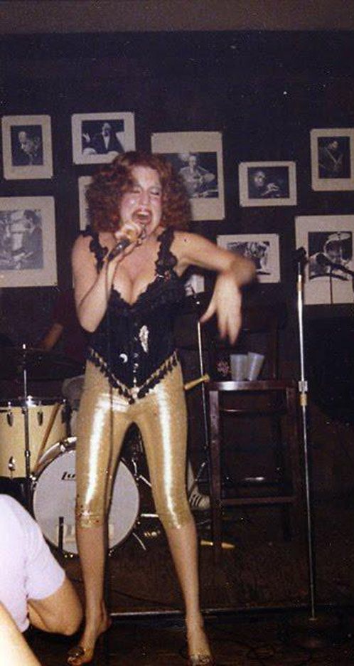 a woman in gold pants singing into a microphone