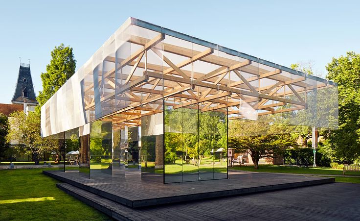 a glass covered building sitting on top of a wooden platform in the middle of a park