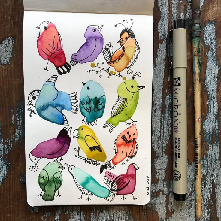 a drawing of colorful birds sitting on top of a piece of paper