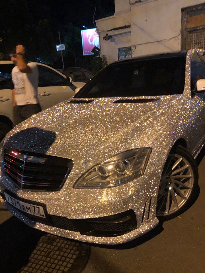 a car covered in silver glitter parked on the side of a street next to a building