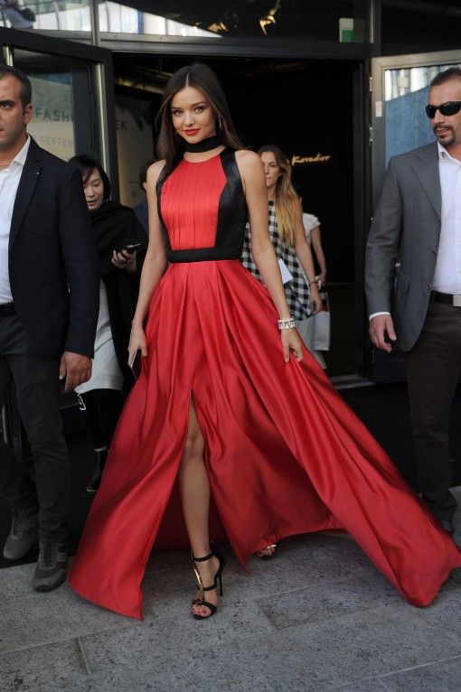 a woman in a red and black dress is walking down the street with other people