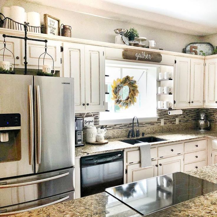 a kitchen with white cabinets and granite counter tops, stainless steel appliances and an island in the middle