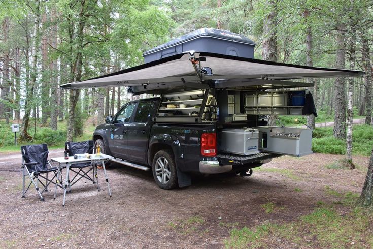 a truck with a camper attached to it parked in the woods