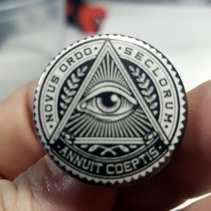 a person holding a badge with an all seeing eye on it