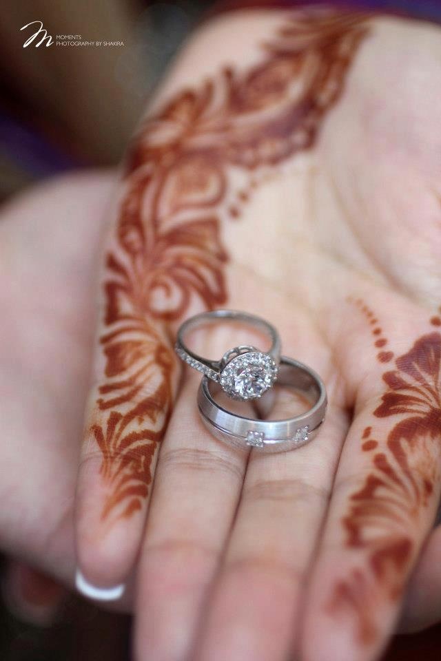 two wedding rings sitting on top of someone's hand with hennap painted on it