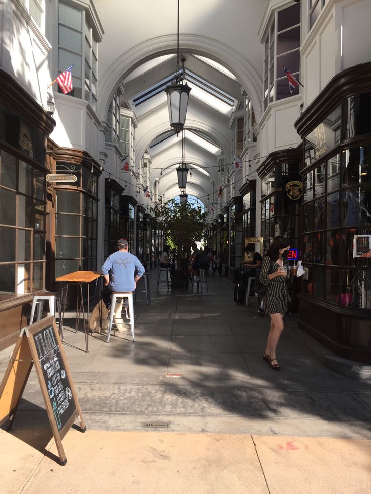 a man is standing in the middle of an empty shopping mall with tables and chairs