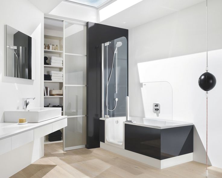 a modern bathroom with white and black fixtures, wood flooring, and skylight