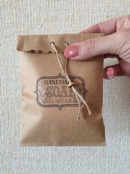 a hand holding a brown paper bag with twine and string on the top that says thunder soap