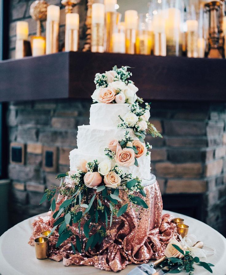 a three tiered wedding cake with pink flowers on top and gold sequins