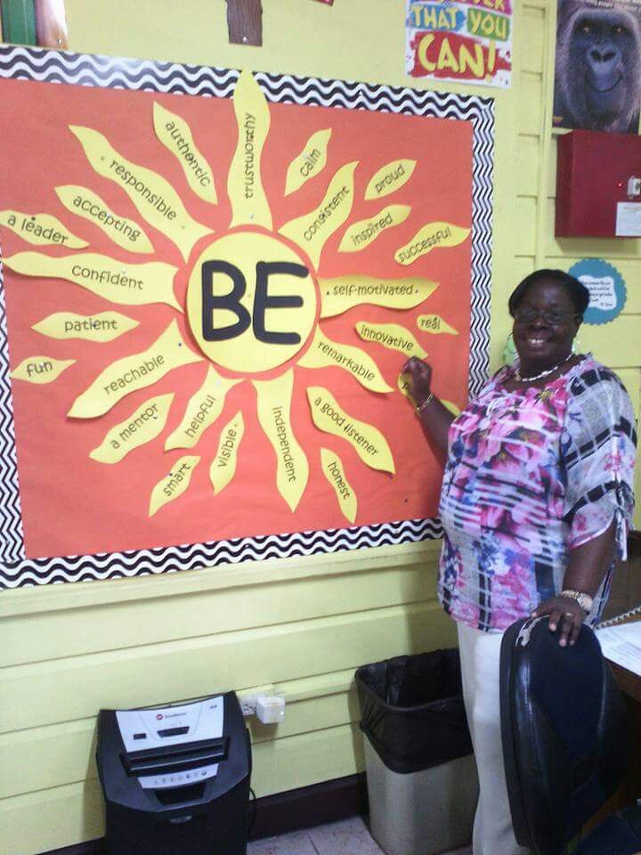 a woman standing in front of a bulletin board with the word be written on it