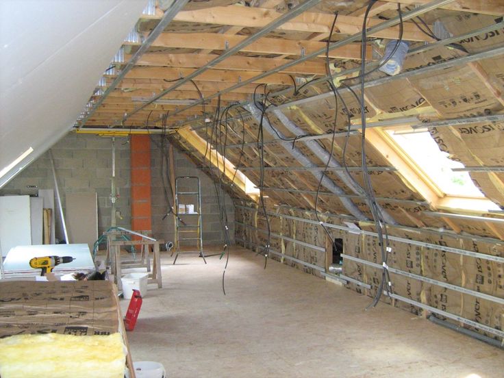 an unfinished attic with wooden beams and ladders on the ceiling, surrounded by construction materials