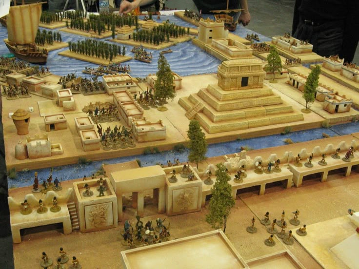 a model of a city with lots of buildings and people standing around it on top of a table