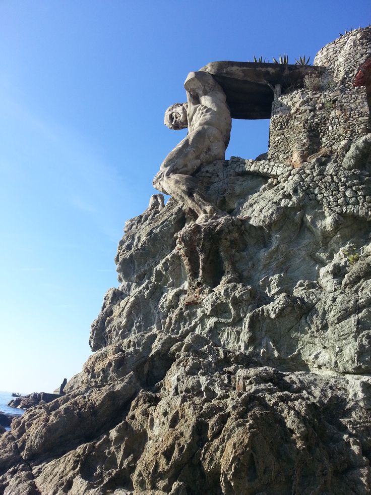 there is a statue on top of a mountain with a blue sky in the background