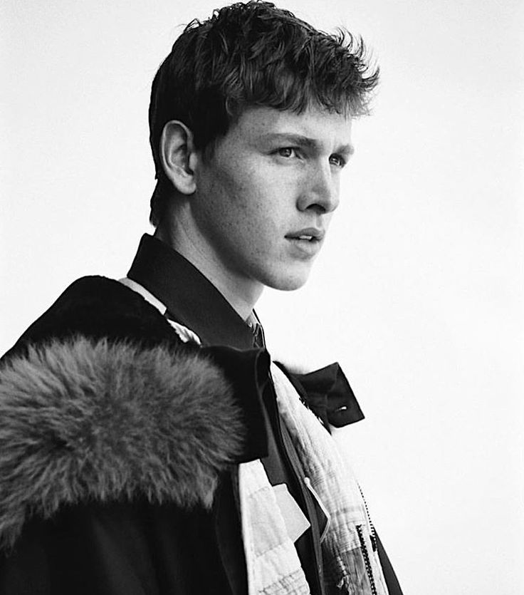 black and white photograph of a young man wearing a jacket with a fur lined collar