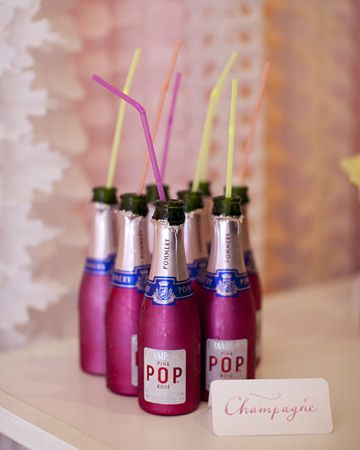 four bottles with drinking straws in them sitting on a table next to a sign