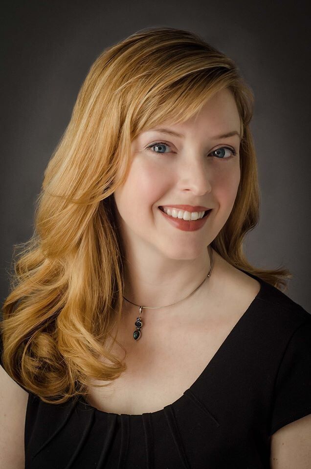 a woman with blonde hair and blue eyes smiles at the camera while wearing a black dress