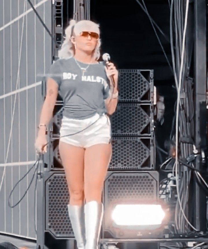 a woman in short shorts and knee high boots holding a microphone