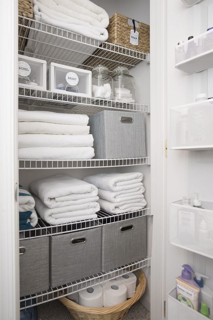 an organized closet with white linens and baskets