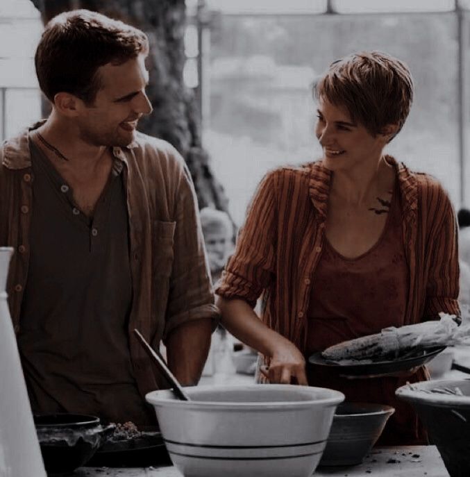 a man and woman standing in front of a table full of bowls with plates on it