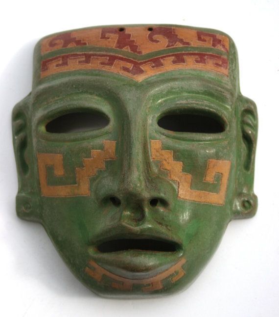 a green mask with gold and red designs on it